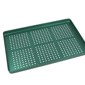 Grünes gelochtes Aluminiumtray zur Organisation von Dentalinstrumenten.