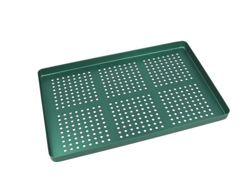Grünes gelochtes Aluminiumtray zur Organisation von Dentalinstrumenten.