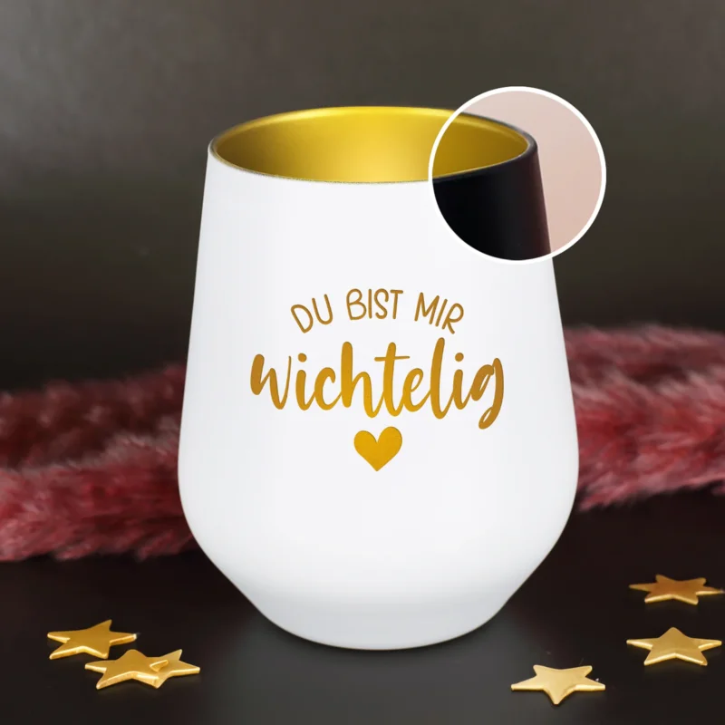 Schwarzes Windlicht mit goldener Innenbeschichtung und der Gravur „Du bist mir wichtelig“ auf dunkler Dekofläche
