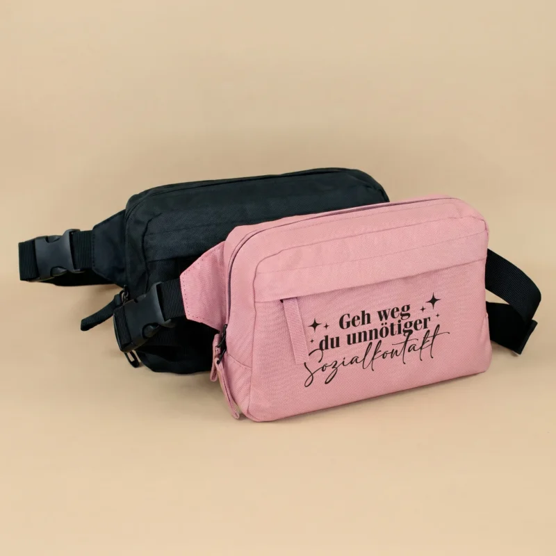 Rosa und schwarze Bauchtasche mit Spruch Geh weg du unnötiger Sozialkontakt auf beigem Hintergrund